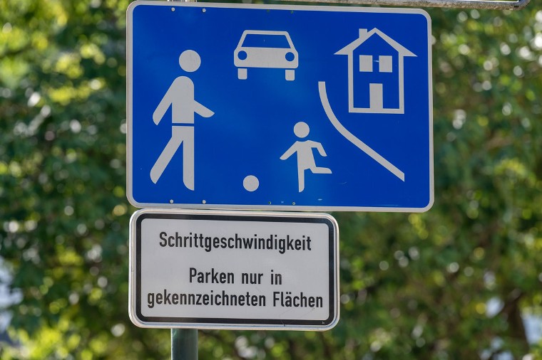 Spielstraße mit Piktogramm, Poller, markierten Parplätzen, versetzen Parkflächen und Spielbereich