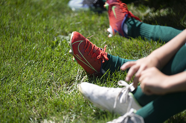 Kinderfüße mit Fußballschuhen auf einer Wiese