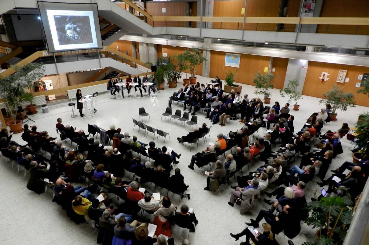Publikum sitzt bei einem Vortrag in einer Aula