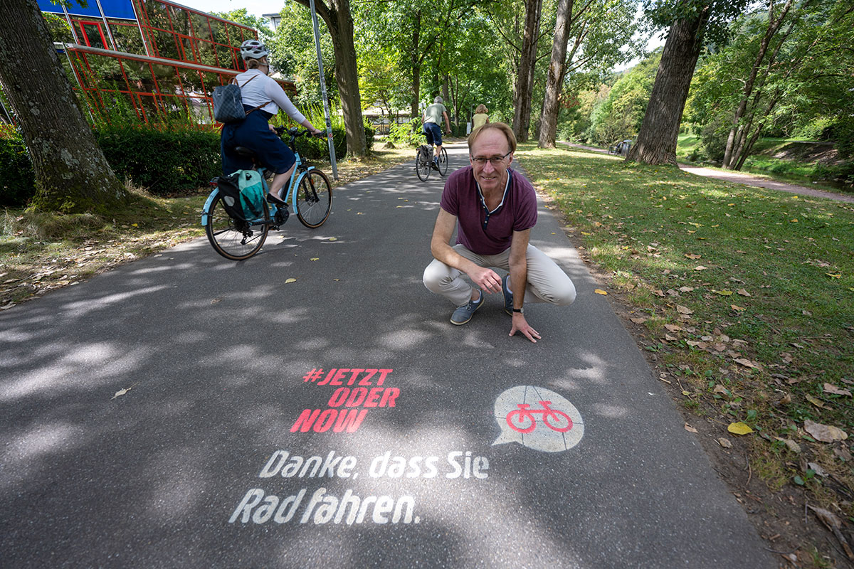 Baubürgermeister Prof. Dr. Martin Haag präsentiert auf einem Radweg die Dankesbotschaft an die Radfahrenden