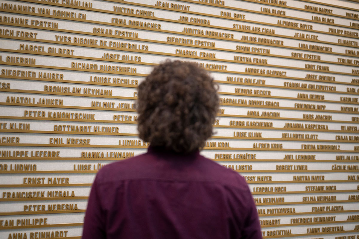 Person steht vor einer Wand mit ganz vielen Namen